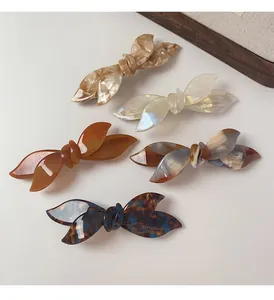 Detailed macro view of 5-piece acetate bow hair clips with refined marble texture
