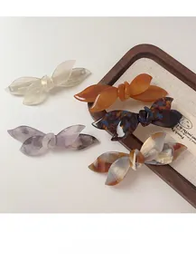 Close-up of acetic acid bow hair clips in pearl white and tortoiseshell textures