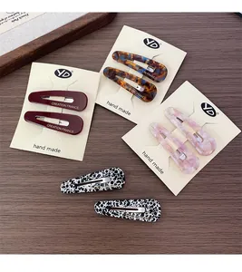 Detailed close-up of acetate BB hair clips with France stamp on wood background