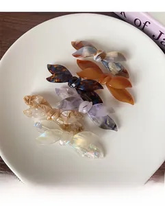 Detail of elegant acetate bow hair clips with marble texture and golden logo lettering