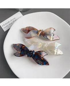 Detailed macro view of three bow-shaped acetate hair clips with elegant marbled textures