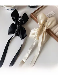 Détail de pinces à cheveux à nœud en satin avec de longs rubans en noir et beige crème