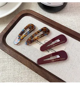 Detail of vintage French teardrop hair clips in tortoiseshell and burgundy on wooden tray