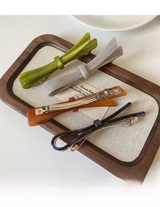 Detailed macro shot of premium acetate hair clips in varied marble textures on wood tray