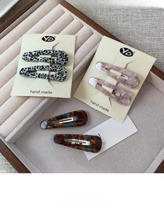 Detail of teardrop acetate hair clips with leopard and marble patterns on wooden display