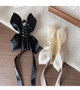 Détail de pinces à cheveux à nœuds en soie noir et crème avec de longs rubans élégants
