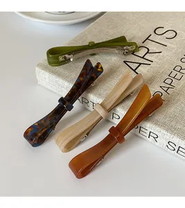 Detail showing four acetate bow hair clips in olive green, tortoiseshell, and amber