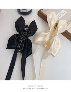 Détail de pinces banane à nœud en satin avec longs rubans en noir élégant et champagne