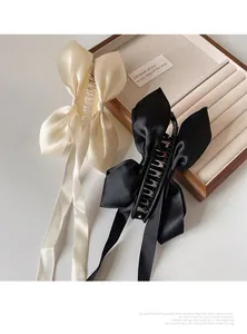 Détail de pinces à cheveux en satin élégantes crème et noires avec de longs rubans