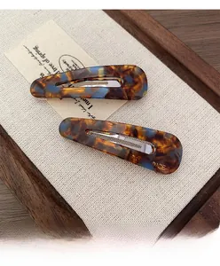 Detail of French vintage tortoise shell hair clips with golden logo on beige linen background
