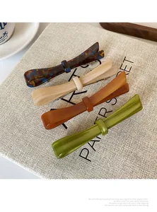 Detailed set of four acetate ribbon hair clips in tortoiseshell and beige on a canvas bag