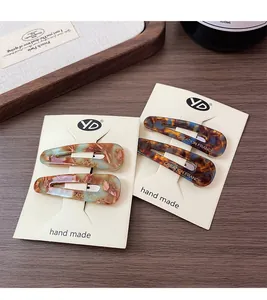 Detail of four acetate drop hair clips with vintage tortoiseshell patterns on display card