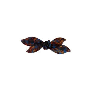 Minimalist acetate bow hair clip with brown tortoise pattern and gold lettering