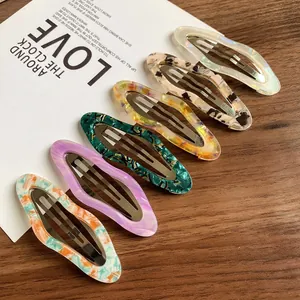 Set of six colorful marble pattern acetate cloud hair clips on a rustic wooden desk