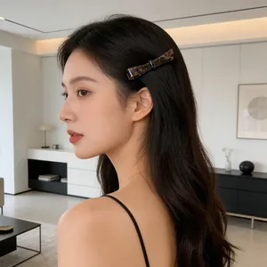 Acetate bow hair clip in tortoiseshell pattern worn on model's wavy dark brown hair
