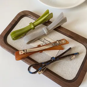 Chic acetate hair clips in four colors including green and amber on a wooden tray