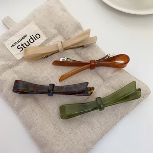 Set of four acetic acid acetate bow hair clips in beige, amber, blue, and green colors