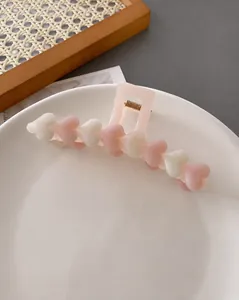 Close-up of heart-shaped hair claw clip with pink and white resin hearts in a ceramic bowl