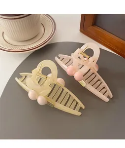 Close-up of cream and pink hair claws with pearls on a cozy lifestyle background
