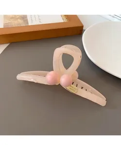 Detail of peach pink resin hair claw clip with golden brand plate and decorative beads