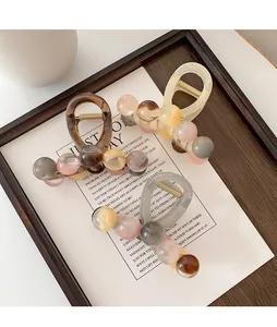Close-up of elegant hair claws with marble beads in brown, beige and grey colors