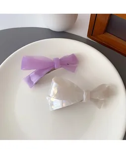 Detail of light purple and pearl white bow hair clips on a ceramic plate for styling