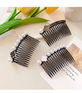 Detail of hair comb featuring smooth faux pearls and clover motif on a dark base