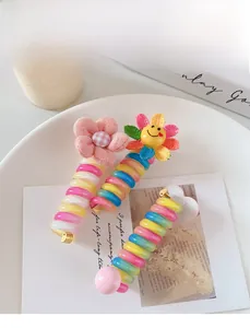 Detail von bunten Regenbogen-Telefonkabel-Haargummis mit Stoffblumen und Smileys
