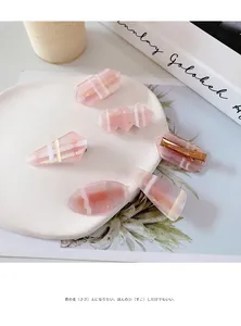 Sechsteiliges Set aus rosa Acetat-Haarspangen mit goldenen Entenschnabel-Clips auf Tablett