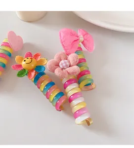 Nahaufnahme von Regenbogen-Spiralhaargummis mit Sonnenblumen und rosa Schleifen