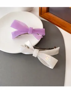 Detail of two-tone matte purple and pearlescent white bow hair claw clips on a plate