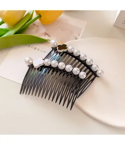 Detail of two pearl hair combs with clover design on a decorative white plate