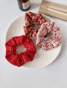 Macro detail of three tweed scrunchies in red and white plaid pattern on ceramic plate