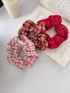 Detail view of three tweed scrunchies in red and beige patterns on an open book