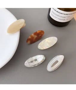 Nahaufnahme von fünf ovalen Haarspangen aus Acetat in Creme, Bernstein und Perlmutt