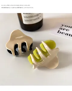Two-tone resin hair claws in beige and green, showing durable teeth and smooth texture