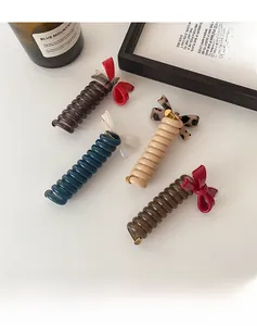 Nahaufnahme von Spiral-Haargummis mit Schleifen in Blau, Braun und Beige auf weißem Grund