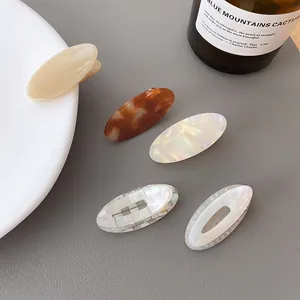 Oval acetate hair claw clips in tortoise shell and cream colors with metal spring