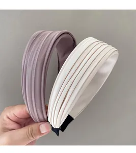 Detailansicht plissierter Stoffstirnbänder in Creme und Altrosa mit seidiger Textur