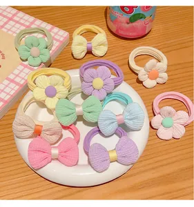 Detail of high-elastic kids hair ties with fabric flowers and bows on wooden table