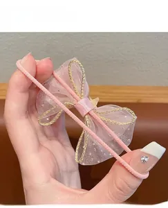 Close-up of pink organza bow hair tie with gold trim and high-elastic woven rope