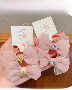 Detail of four pink mesh bow hair ties with glitter edges and crystal heart ornaments