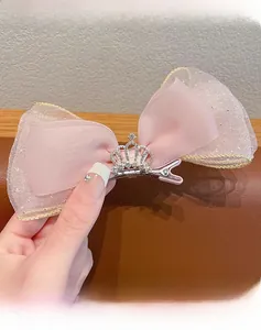 Close-up of pink mesh bow hairclip with golden edges and a silver crown rhinestone detail
