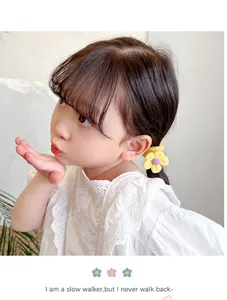 Close-up of a child wearing a soft yellow flower hair tie on a neat ponytail