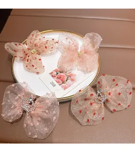 Detail of pink bow hair clips with glitter tulle, heart prints, and crown rhinestones