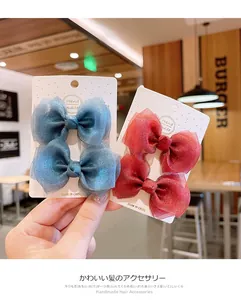 Close-up of glitter mesh bow hair clips in blue and red on handmade display card