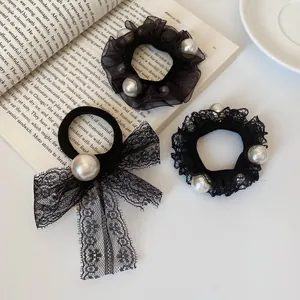 Set of 3 elegant black pearl hair ties with lace and mesh on an open book background