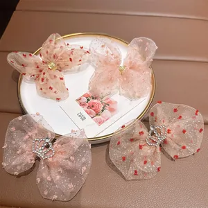 Pink polka dot bow hair clips for girls with rhinestone crown detail on a white tray