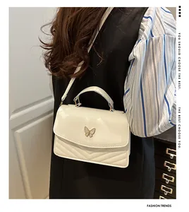 Moderne weiße Stepptasche mit Schmetterlingsschnalle getragen als Umhängetasche