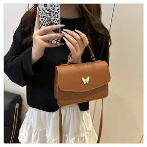 Détail du sac bandoulière marron avec fermoir papillon et coutures en V matelassées